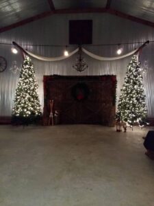 A barn with christmas trees in the middle of it.